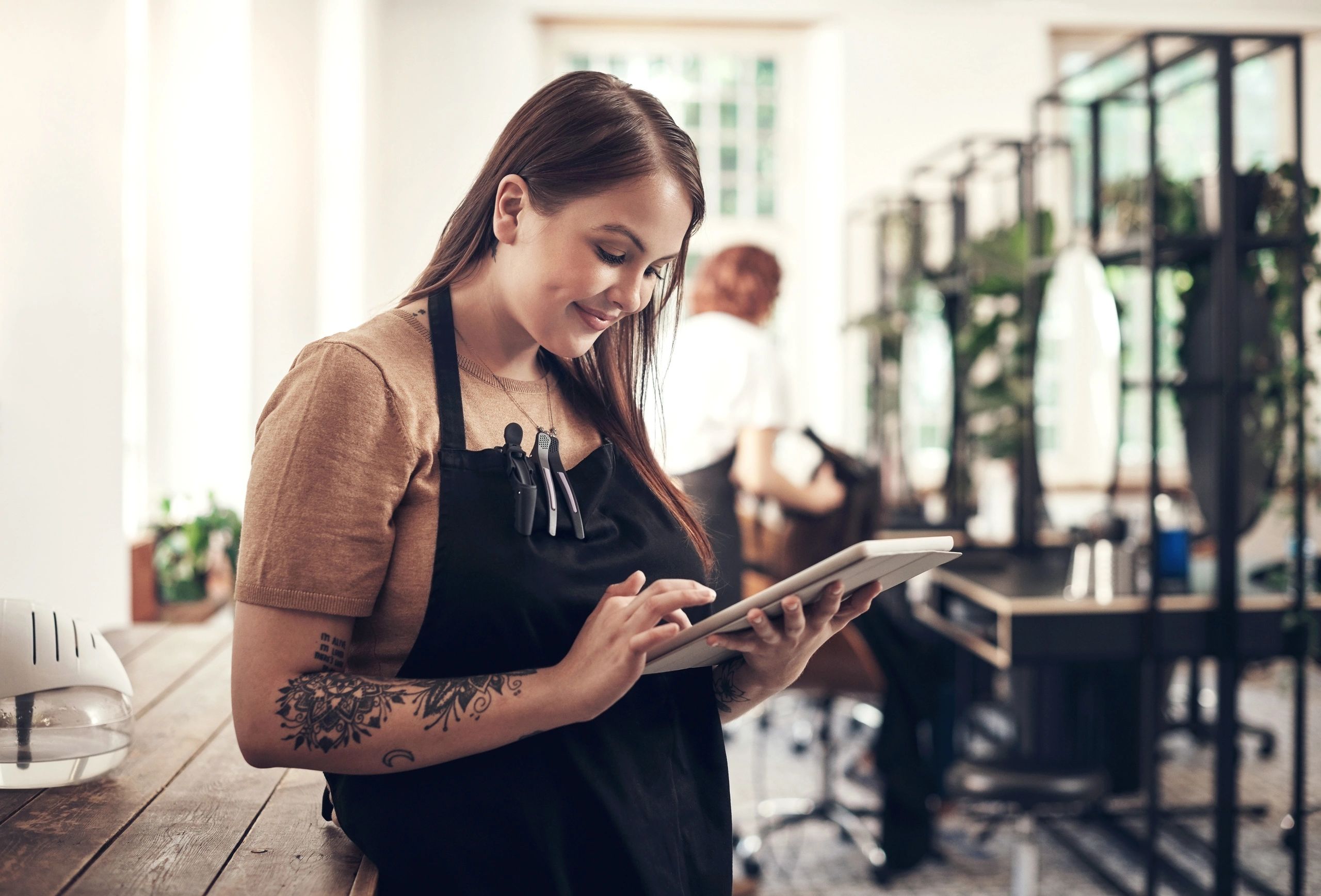 A smiling barista checks a tablet in a cozy cafe.