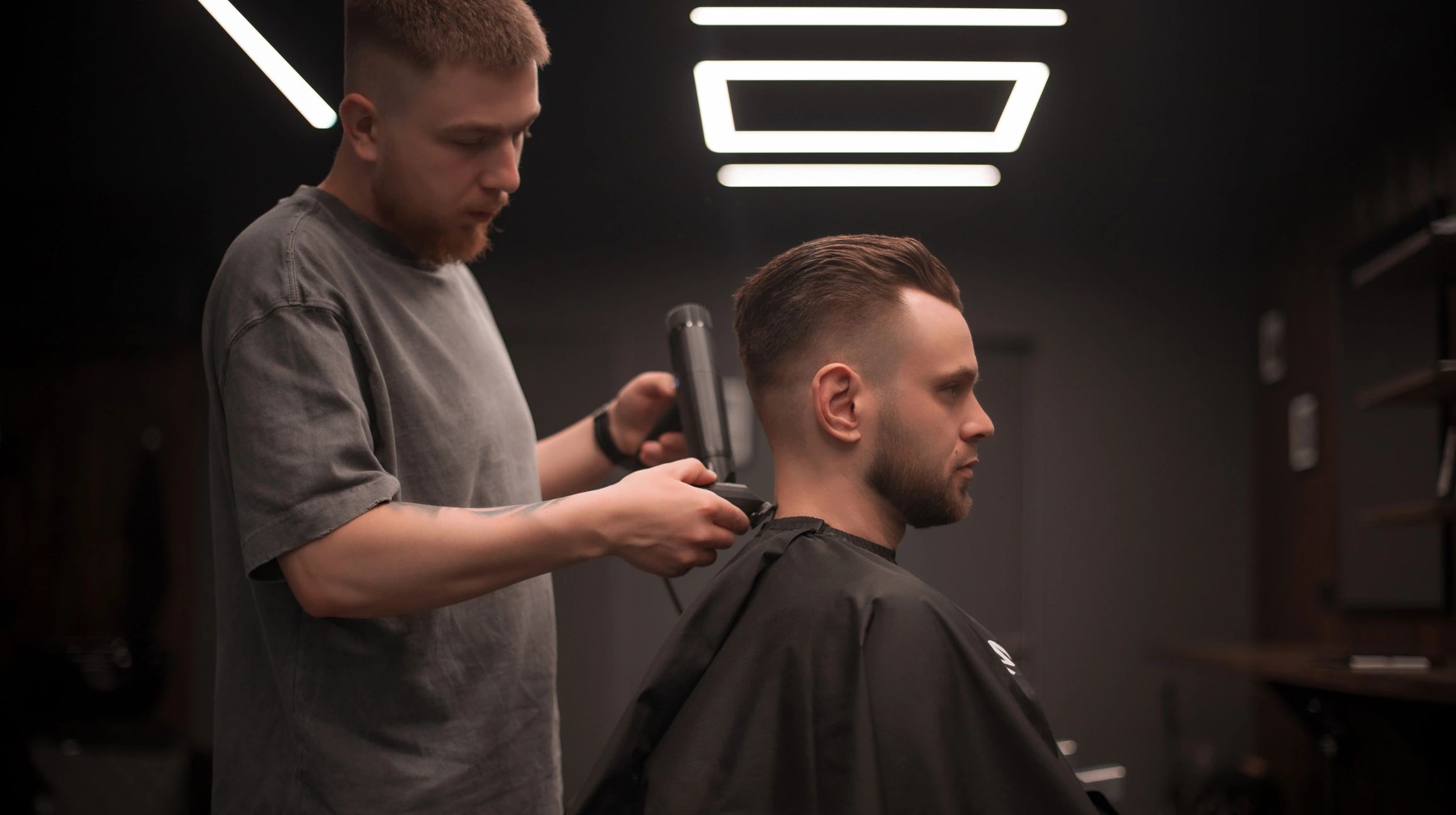 Barber giving a man a haircut in a modern salon.
